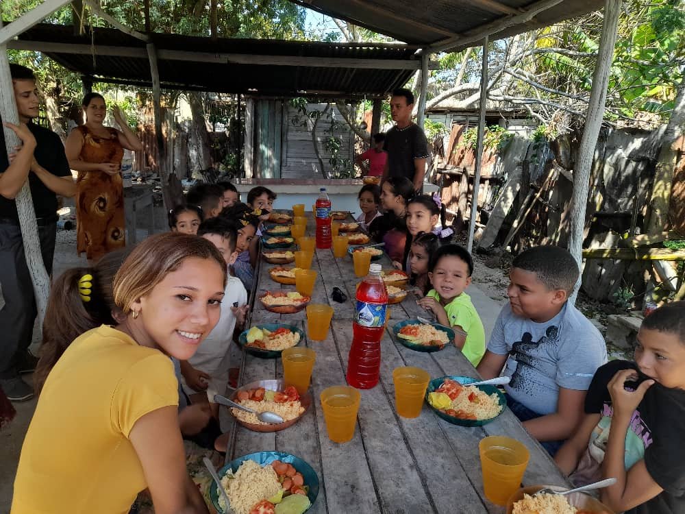 Volunteers and children sharing a meal together at a mission feeding event in Cuba