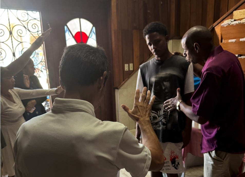 Team praying with church members in Cuba